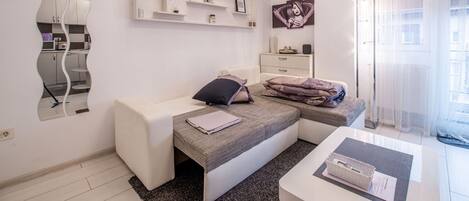 A modern bedroom with a bed, bedside tables, a mirror, and a window with curtains.