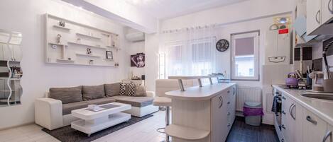 Relax in a spacious living area with a comfortable sofa set and a compact kitchen featuring essential appliances.