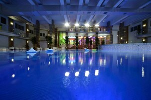 Una piscina interior con agua cristalina, rodeada por un edificio moderno de varios pisos y balcones.