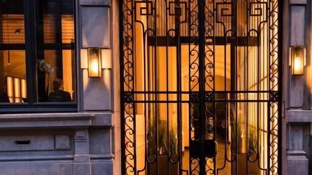 A historic building entrance with a decorative iron gate and a glass enclosure. - Harmon House (Brussels)
