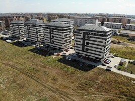 Un edificio residencial de gran altura con varios pisos, un estacionamiento y una zona de construcción cerca.