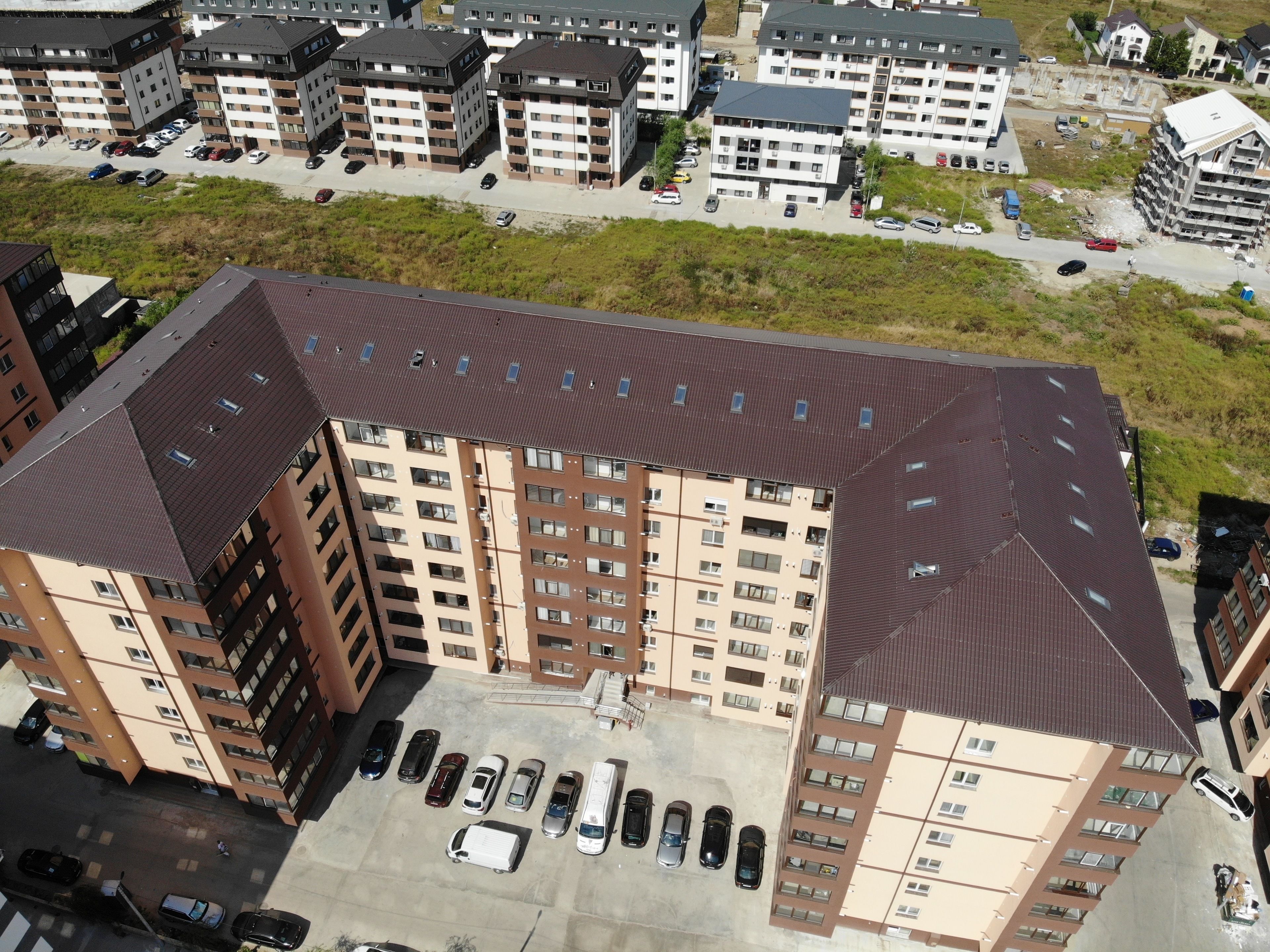 A multi-story residential building with a parking lot in front.