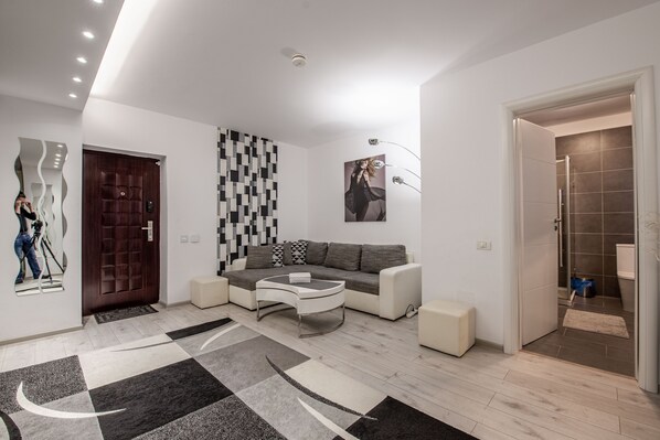 A modern living room with a sofa, coffee table, and patterned rug. - Studio Militari Residence M2 (Chiajna)