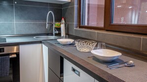 A modern kitchen with a built-in oven, a stainless steel sink, and a window above the counter. - Studio Militari Residence M2 (Chiajna)