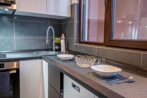 Una cocina moderna con horno integrado, un lavamanos de acero inoxidable y una ventana sobre la encimera.