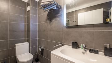 Een moderne badkamer met toilet, wastafel en handdoekhouder.