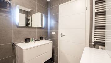 A modern bathroom with a white vanity, a mirror, and a towel rack.