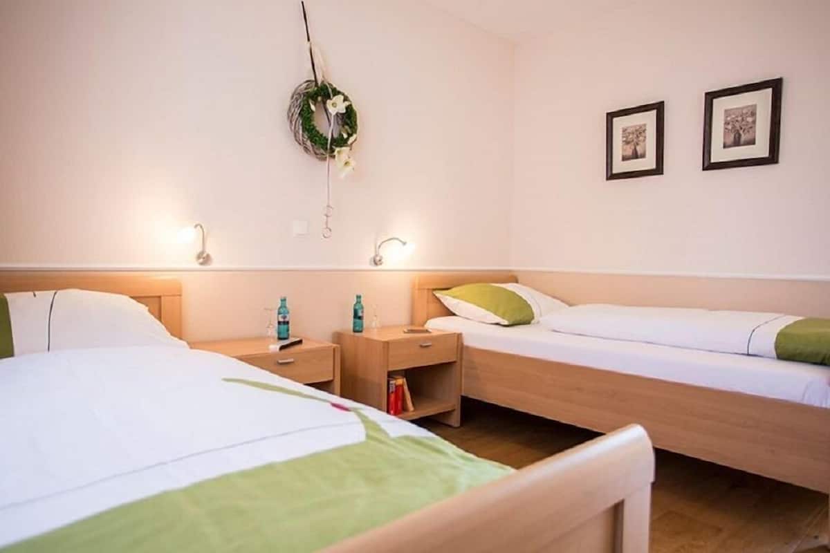 Een hotelkamer met twee enkele bedden, een nachtkastje met een lamp, een klein plankje en een aan de muur bevestigd krans.