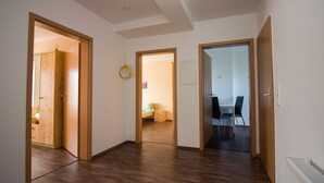 Ein Korridor mit Holzboden und Türen zu einem Schlafzimmer und einem Essbereich.