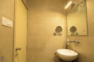 A bathroom with a white sink, a mirror, and a shower.