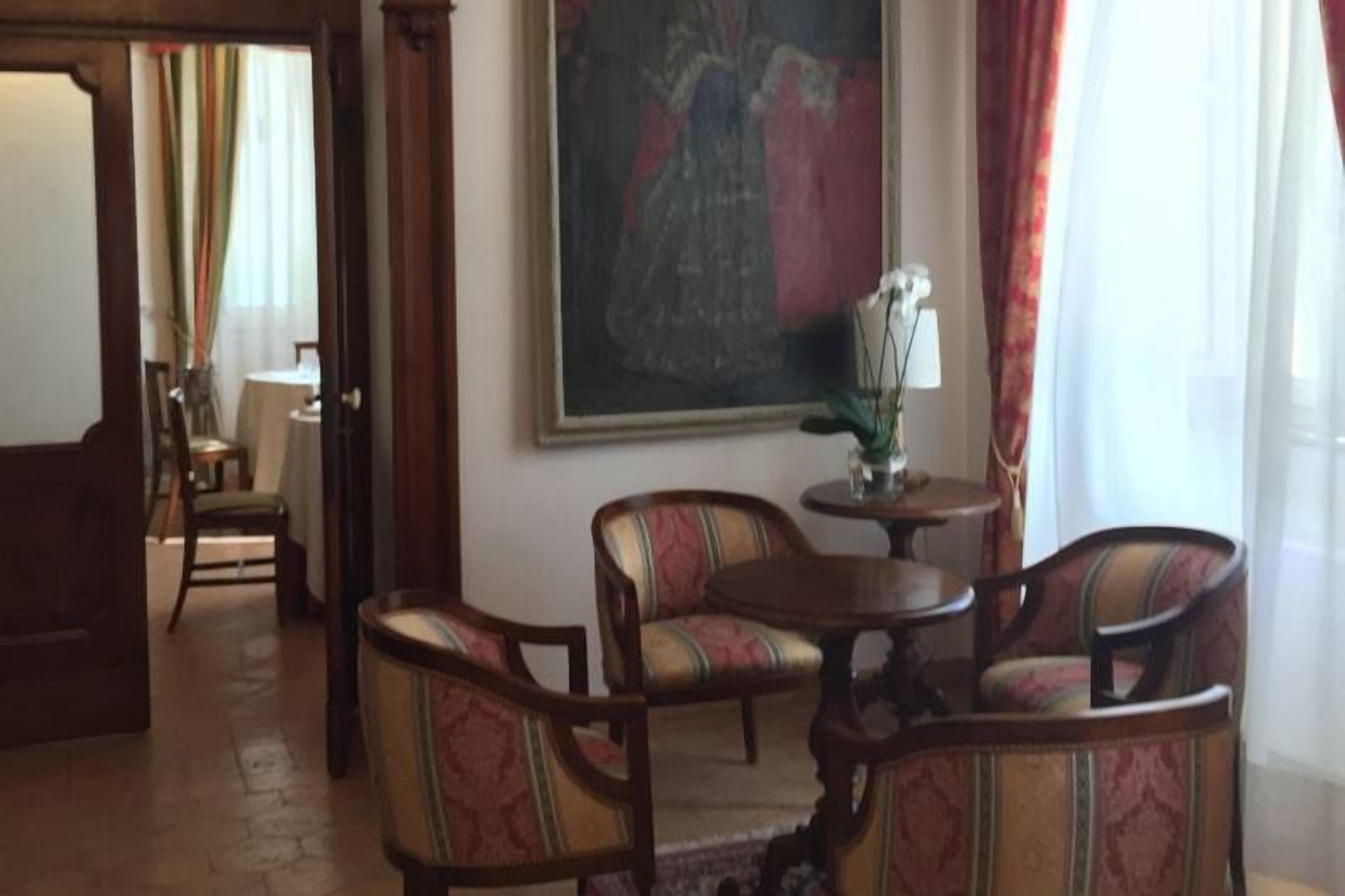 Una habitación con una mesa de comedor y cuatro sillas, un cuadro en la pared y una ventana con cortinas.