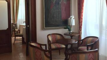 Una habitación con una mesa de comedor y cuatro sillas, un cuadro en la pared y una ventana con cortinas.
