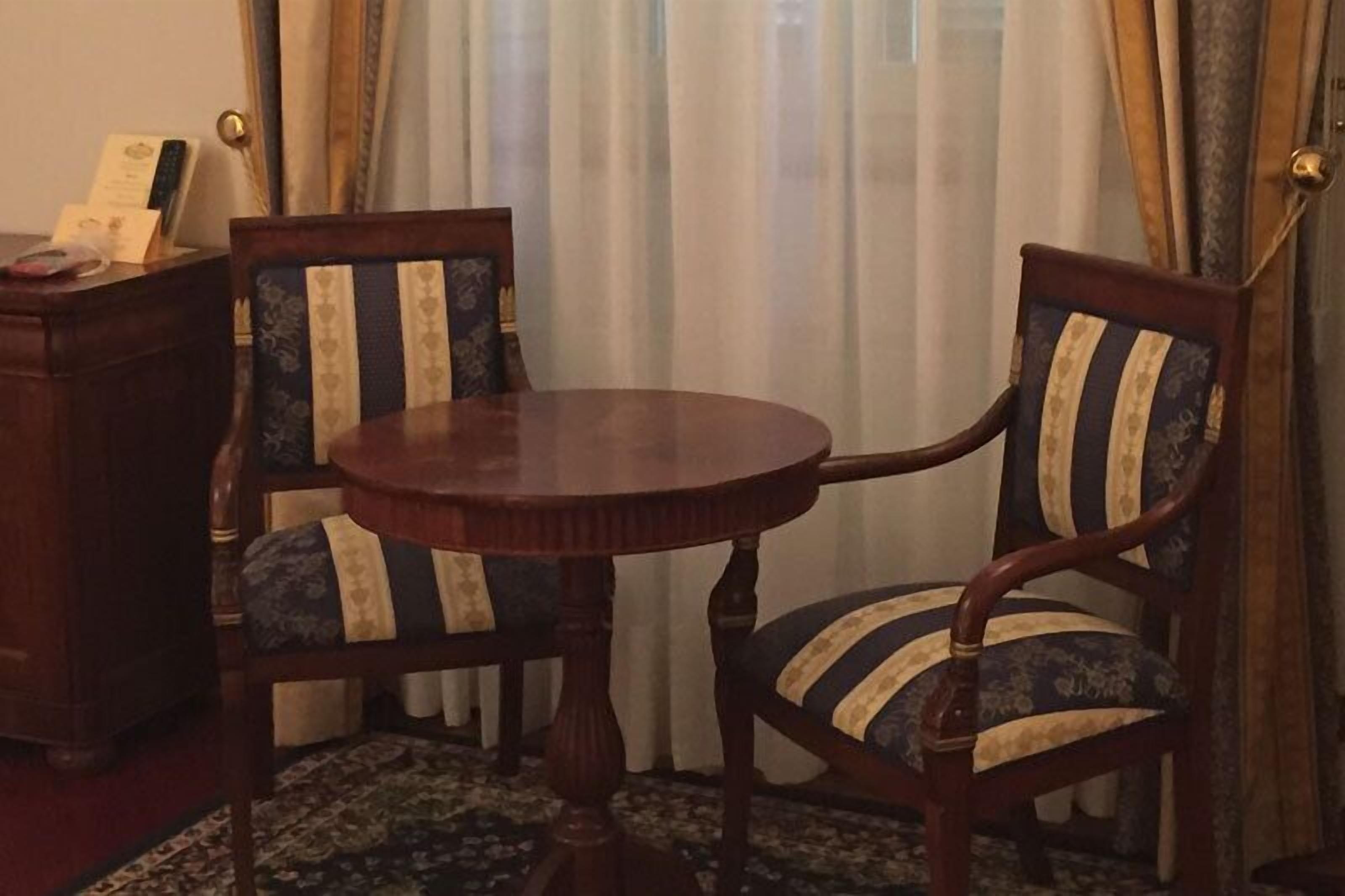 A round wooden table with two upholstered chairs featuring striped patterns.