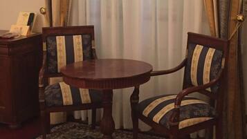 A round wooden table with two upholstered chairs featuring striped patterns.
