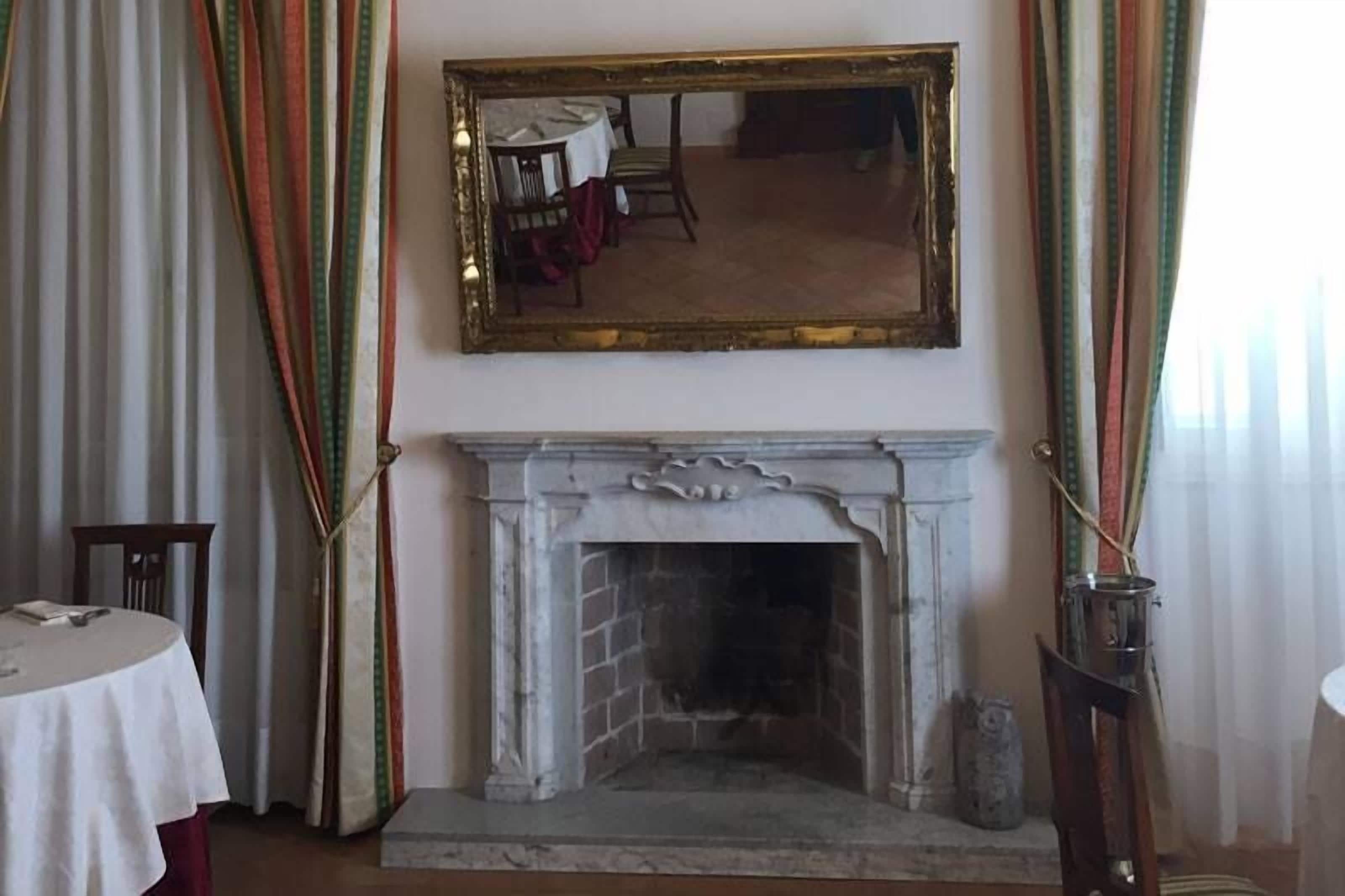 Een kamer met een open haard, een tafel met een wit tafelkleed en een spiegel aan de muur.