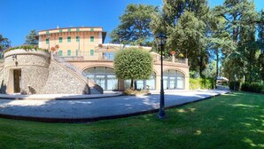 Un edificio con una estructura de piedra circular, una escalera y un césped bien cuidado.