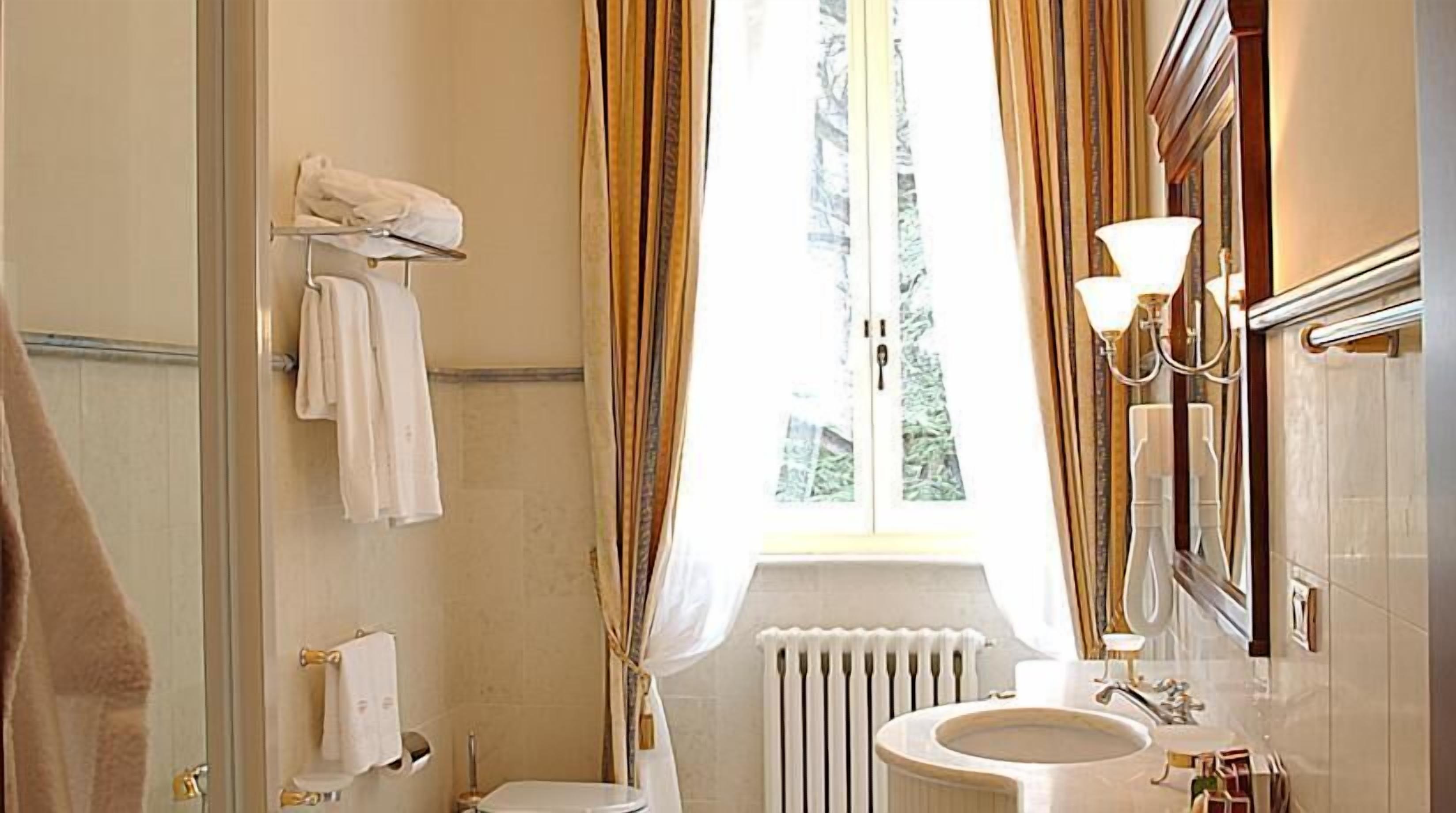 Un bagno con il water, un lavandino e una finestra con tende.