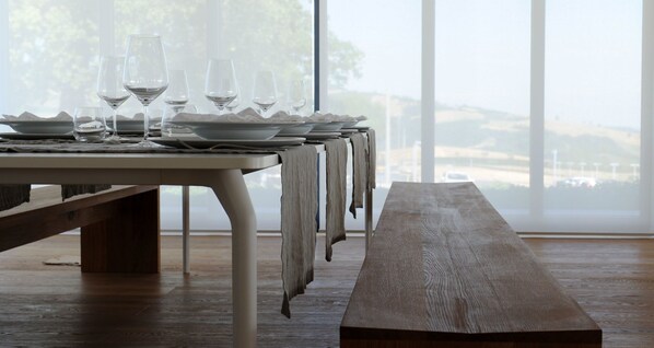A dining table set with plates and wine glasses, with a bench in the foreground.
