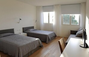 A hotel room with two single beds, a desk, a chair, and a large window with curtains. - Pianderna Agriwellness (Scandiano)