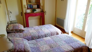 Un dormitorio con dos camas, una estantería, una chimenea y una ventana con cortinas.