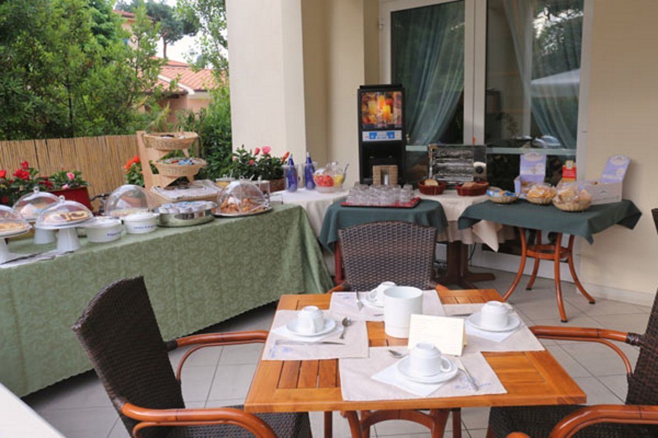 An outdoor dining area with tables set for breakfast, including bread, pastries, and beverages.