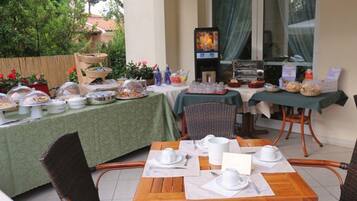 An outdoor dining area with tables set for breakfast, including bread, pastries, and beverages.