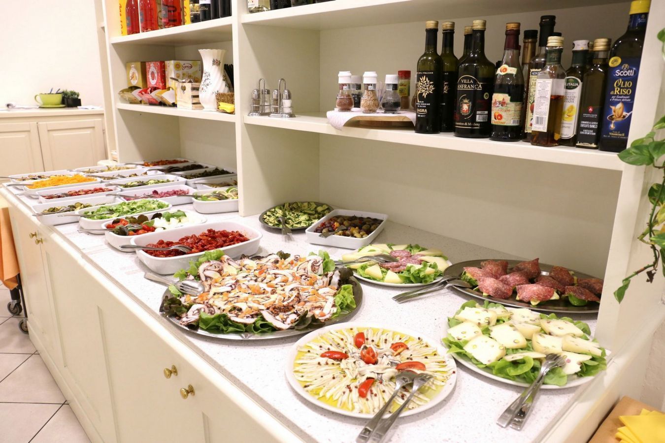 A buffet with various dishes and a selection of olive oils on shelves.