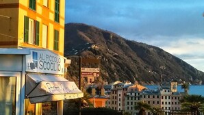 A coastal town with buildings, a mountain, and a sign for 'Al Piccolo Scooglio'. - Al Piccolo Scoglio - Room & Breakfast (Camogli)