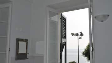 A bathroom with a large window, a mirror, and a view of the sea.