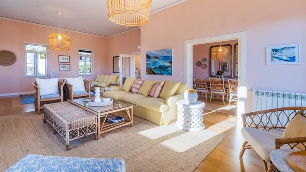 Ein geräumiges Wohnzimmer mit einer großen Couch, Korbmöbeln und einem Essbereich mit Korbstühlen.