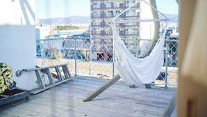 A hammock on a balcony with a view of a building and mountains in the background. - SMALL TOWN HOTEL Hakodate (Hakodate)