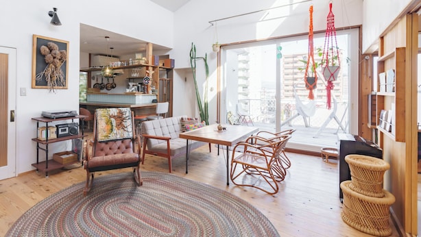A spacious living area with a wooden dining table, comfortable seating, and a large window offering a view of the city. - SMALL TOWN HOTEL Hakodate (Hakodate)
