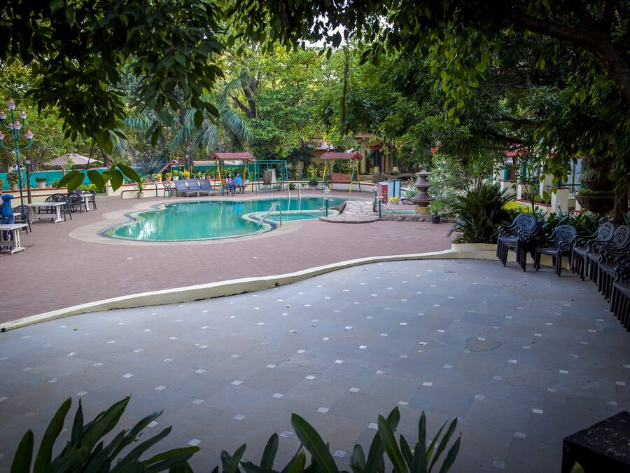 A pool area with a circular pool, seating around the pool, and surrounding greenery.
