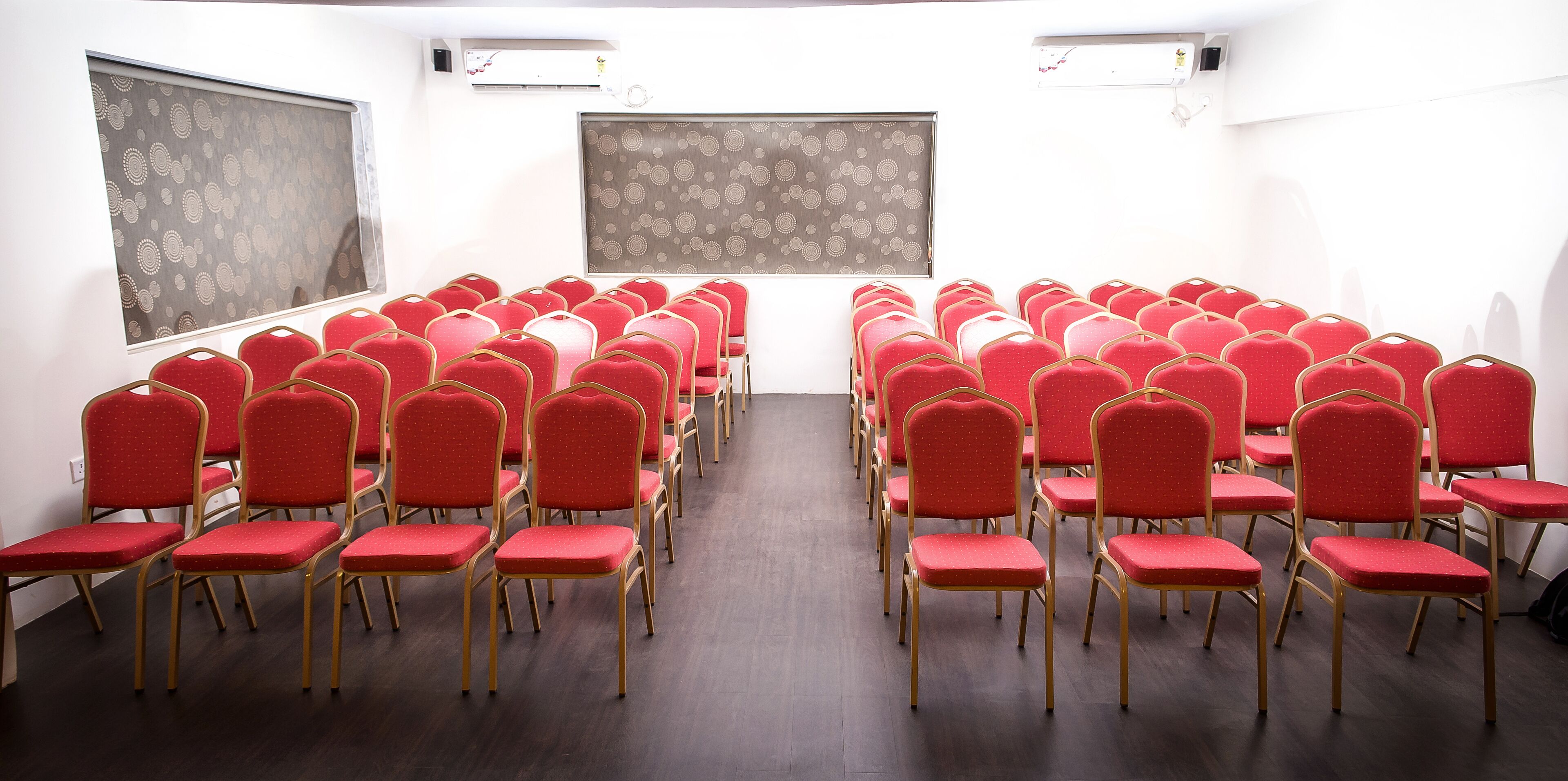 A conference room with rows of red chairs and a large screen at the front.