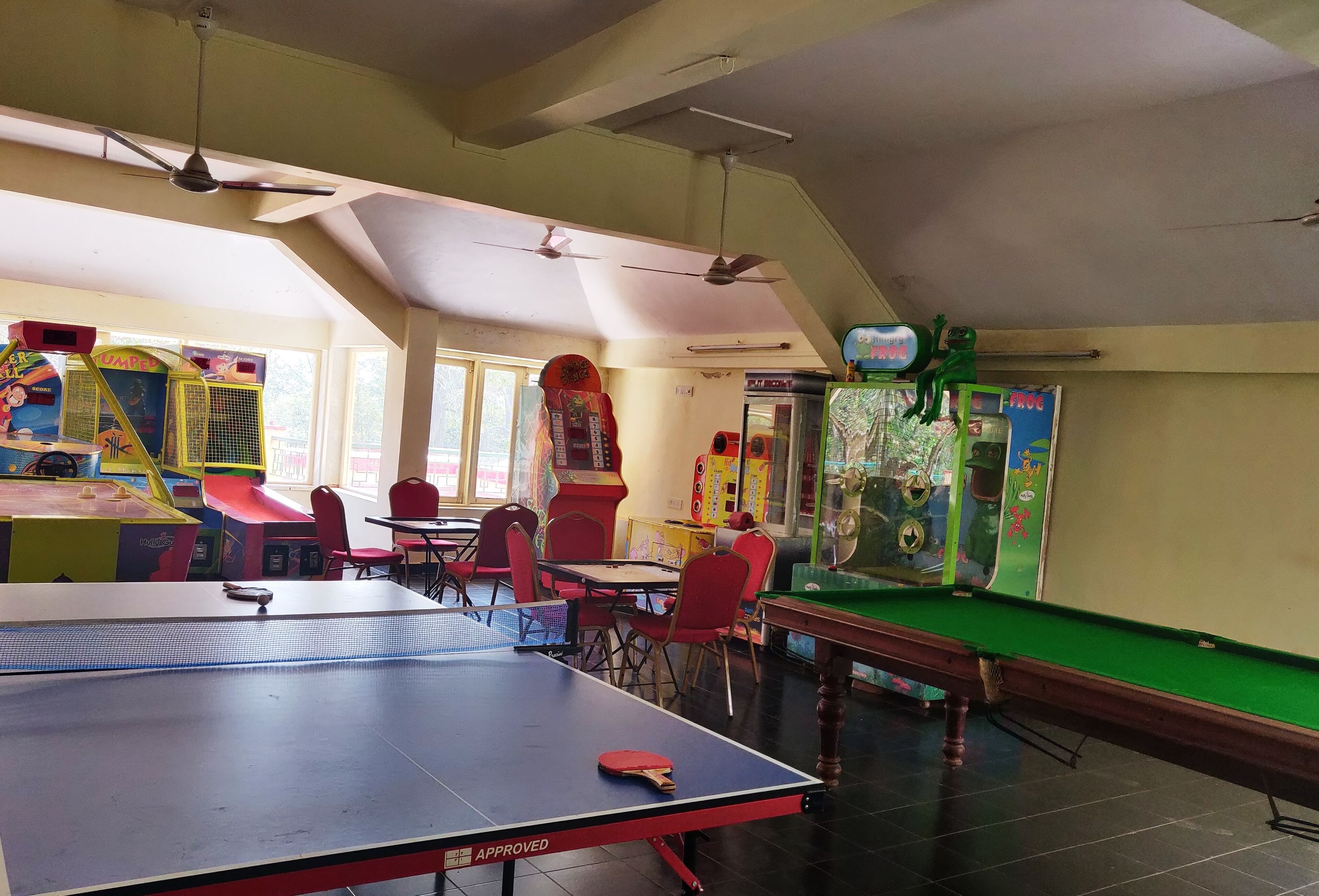 A recreational room with a ping pong table, a pool table, and various arcade games.