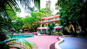 A hotel courtyard with a swimming pool, red-tiled walkways, and lush greenery. - Adamo The Resort (Karjat)