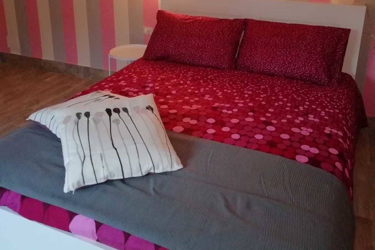 Un dormitorio con cama, almohadas y pared a rayas.