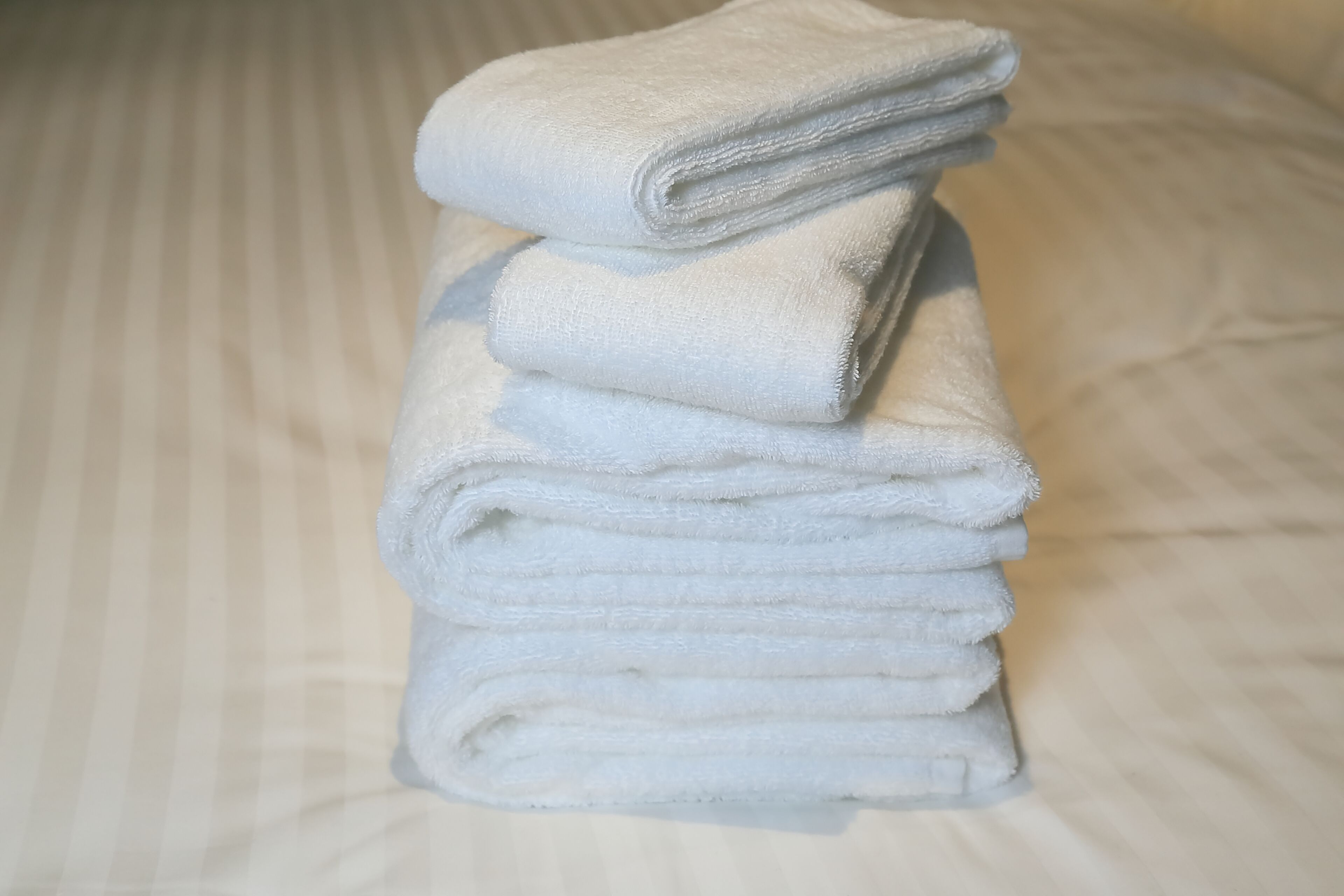 A stack of white towels on a bed with a striped pattern.