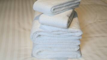 A stack of white towels on a bed with a striped pattern.