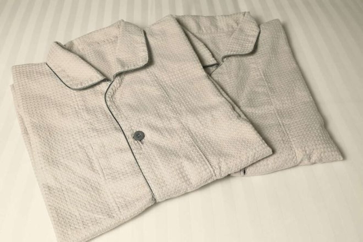 Una camisa clara, bien doblada, con cuello y botones sobre un fondo a rayas.