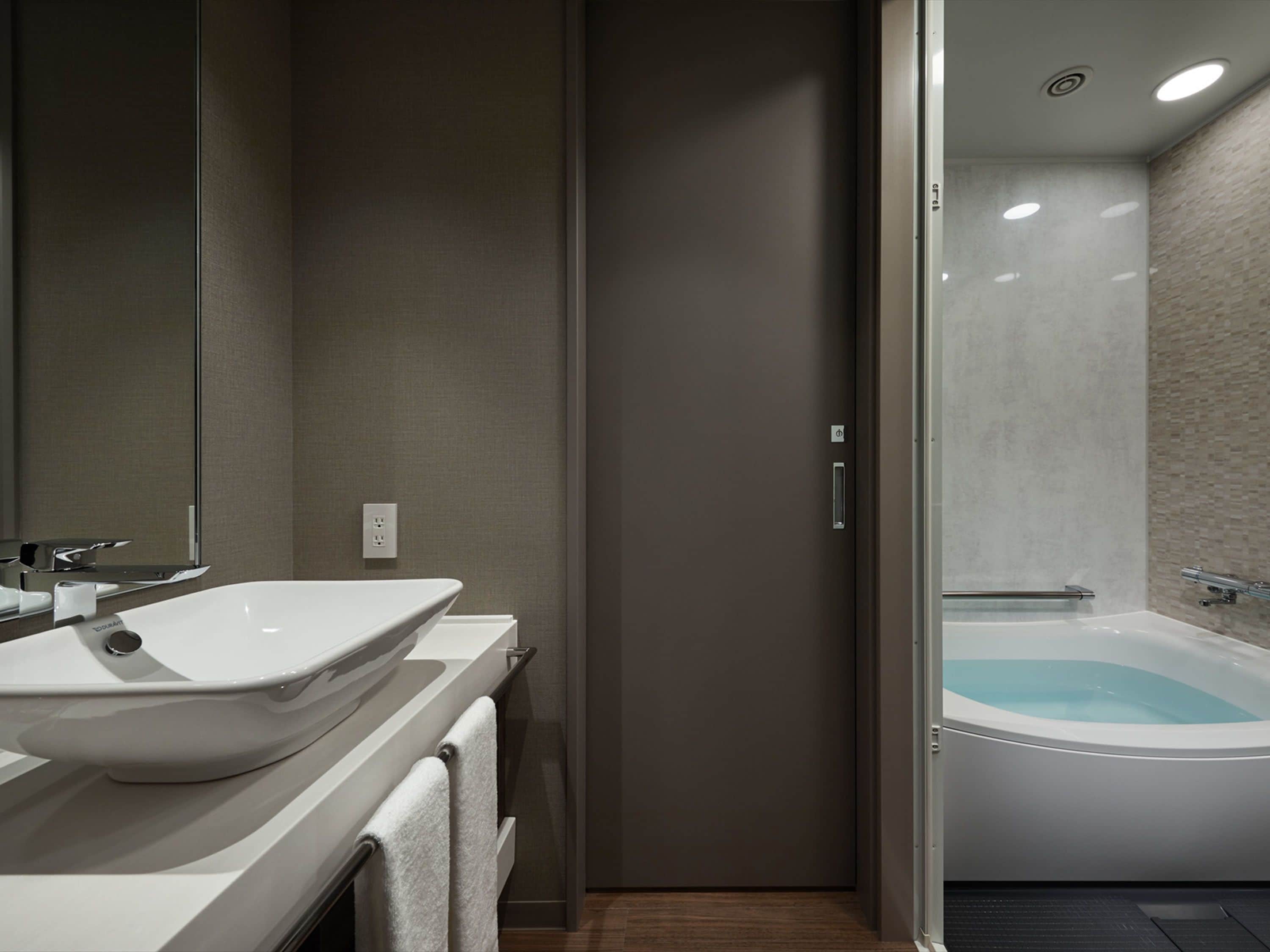 A modern bathroom with a large white sink, a mirror, and a glass-enclosed shower area.