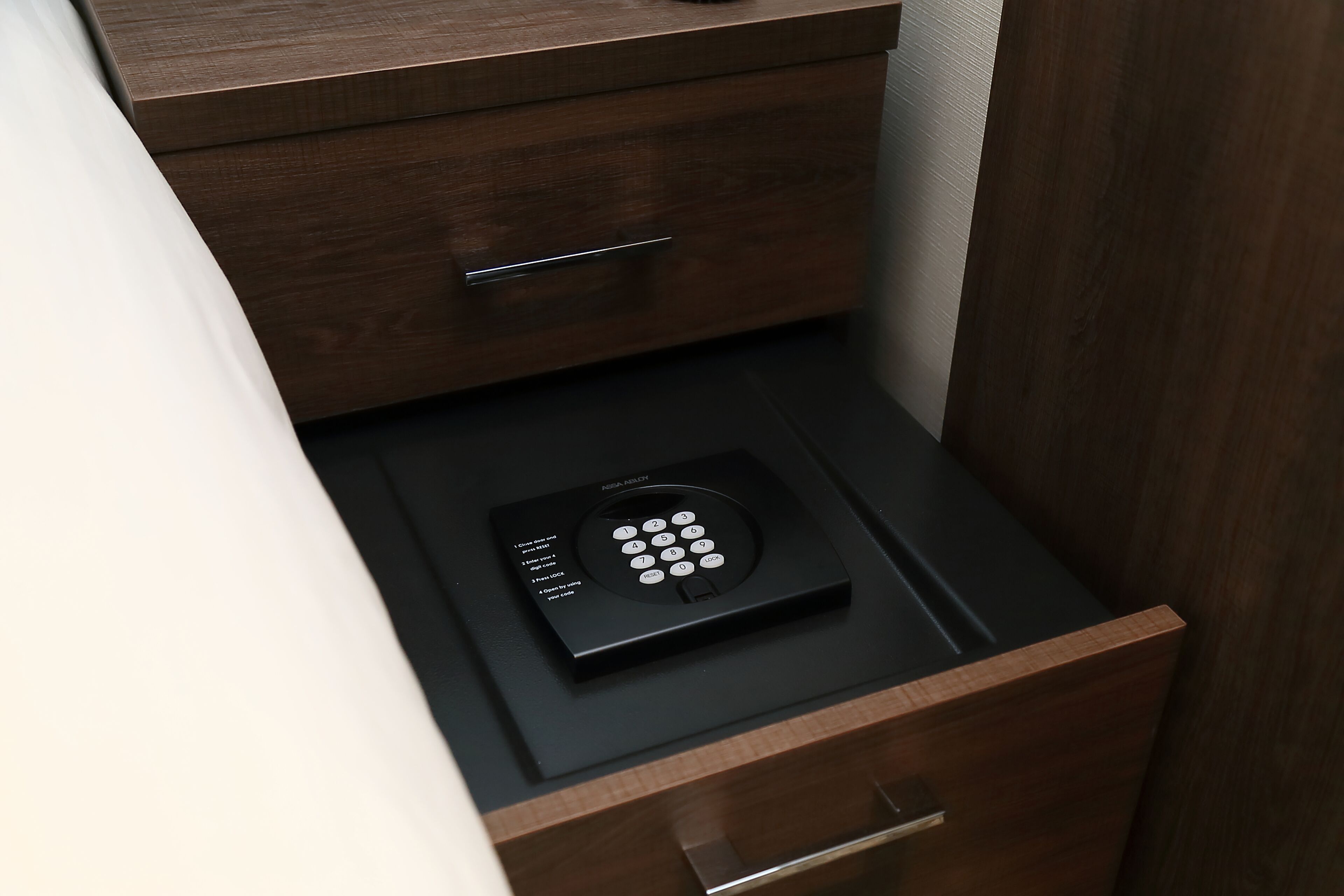A black electronic device on a drawer in a wooden cabinet.