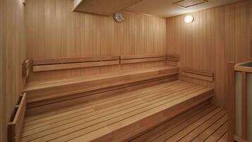 A wooden sauna with multiple benches and a clock on the wall.