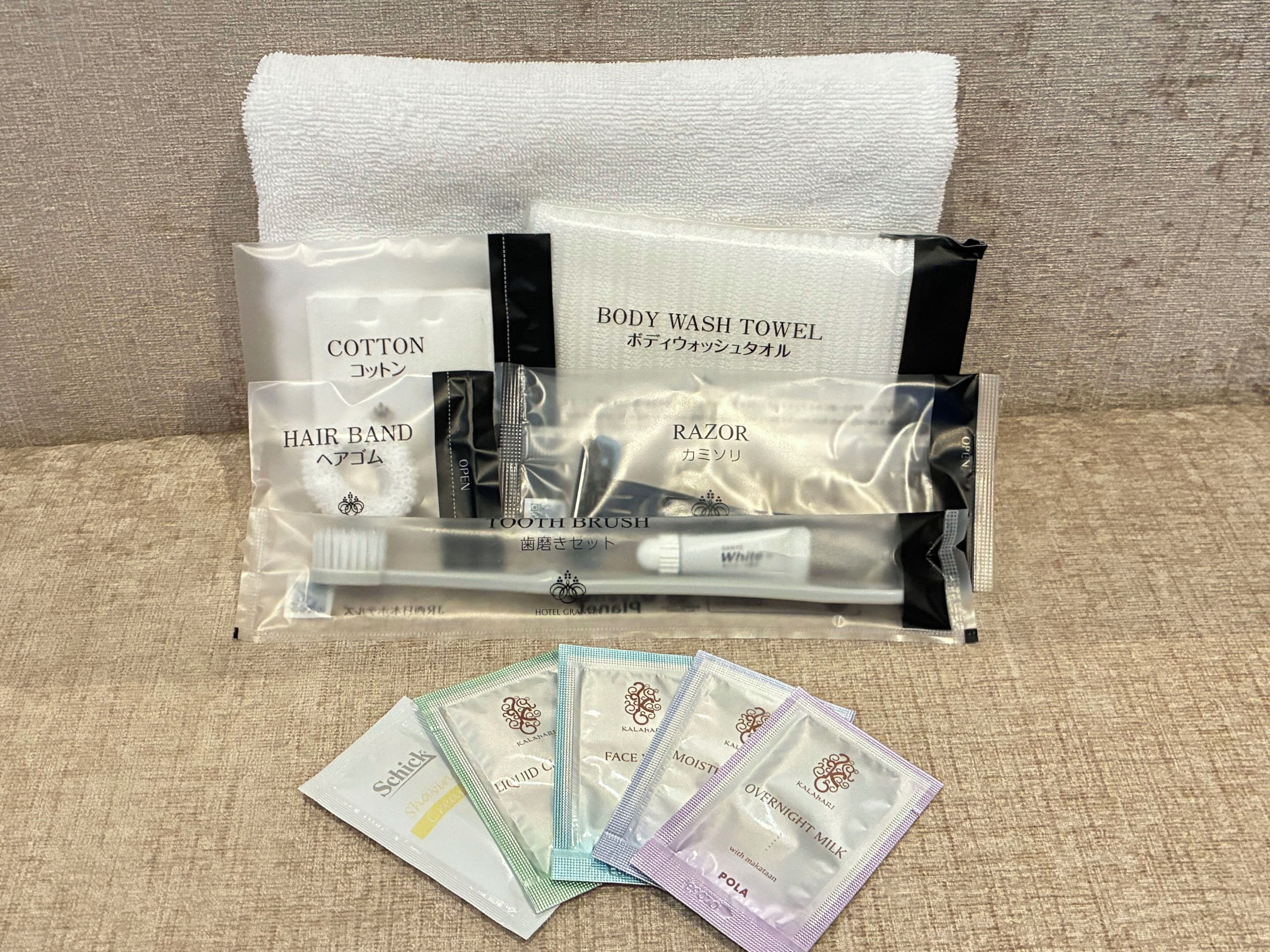 A travel amenity package with a cotton towel, hair band, razor, and tooth brush.
