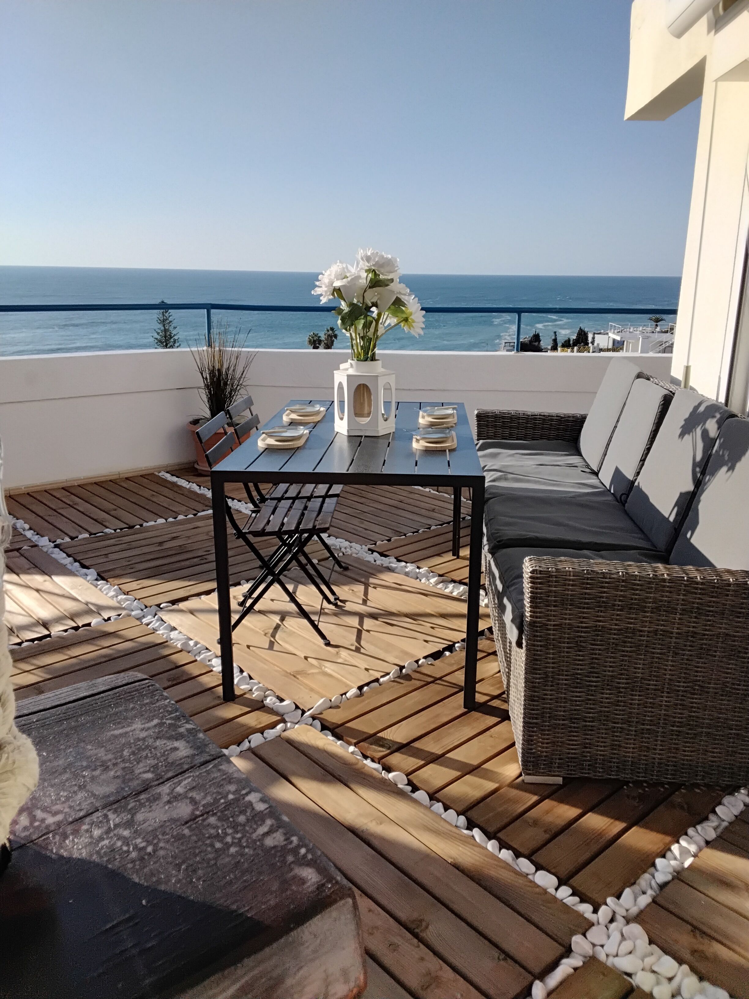 A wooden deck with a table and seating, overlooking a body of water.