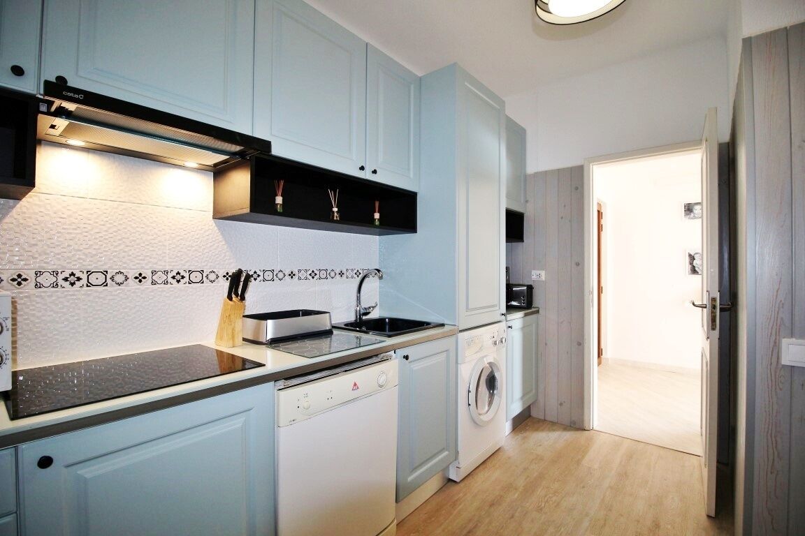 A compact kitchen with a dishwasher, washing machine, and a microwave.