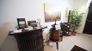 Zona de recepción con mostrador de madera, una planta en maceta grande y un mueble para vinos.