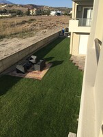 A residential area with a well-maintained lawn, outdoor furniture, and a concrete retaining wall.