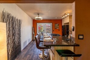Una cucina moderna con zona pranzo, che include un tavolo lungo con sedie, un frigorifero e una lampada a sospensione.