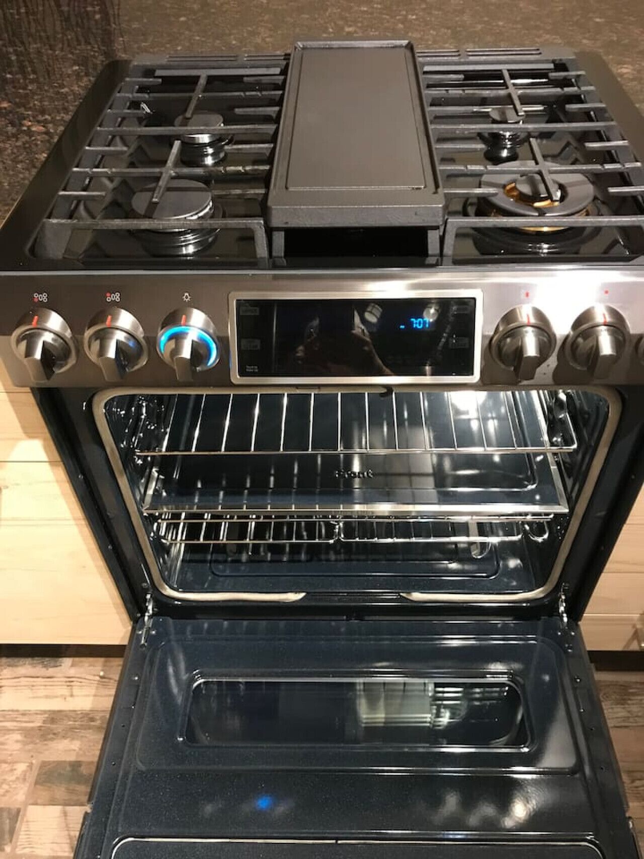 Una cocina con estufa y horno, perillas de control y pantalla digital.